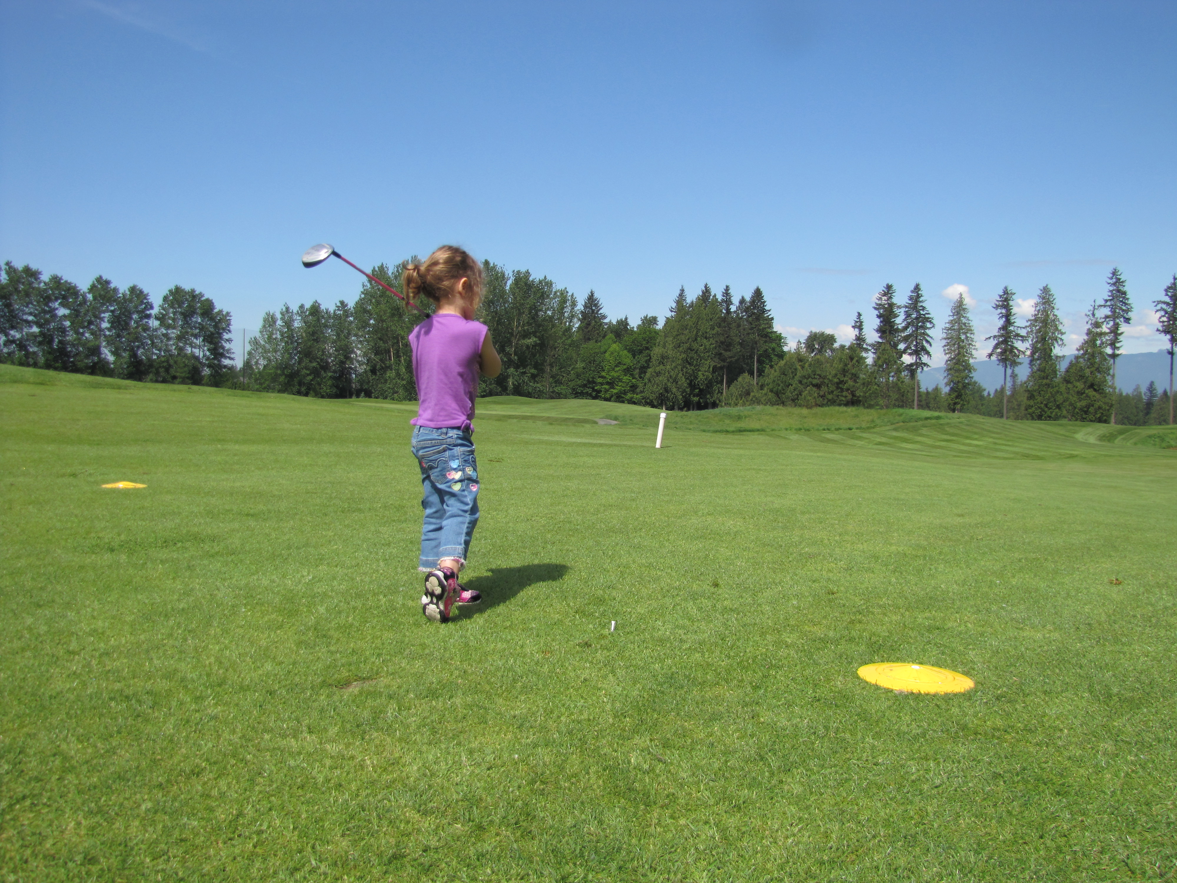 Little girl playing golf swinging the club